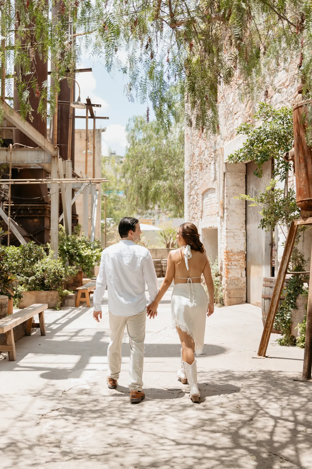 Valeria y Andrés caminando de la mano por un pasillo con árboles